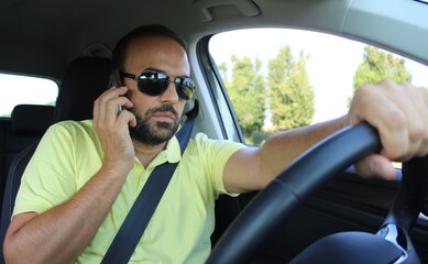 Uomo che guida l'automobile mentre parla al cellulare - illegale e pericoloso