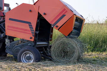 The mini baler collects hay in the field.