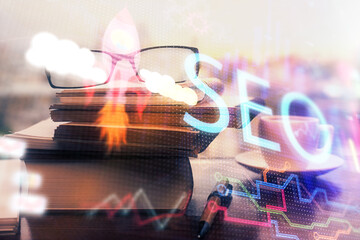 SEO hologram with glasses on the table background. Concept of search engine optimization. Double...