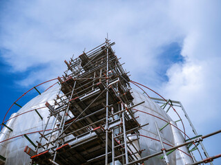 White storage tank with scaffolding structures and clear blue sky on the background.
