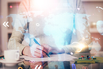 Multi exposure of hands making notes with world map hologram and data theme icons. Concept of global computer data.