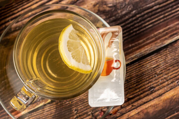 Delicious beverage with mint, honey, lemon and ginger in tea set on wooden background