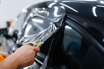 Worker holds film, car tinting installation