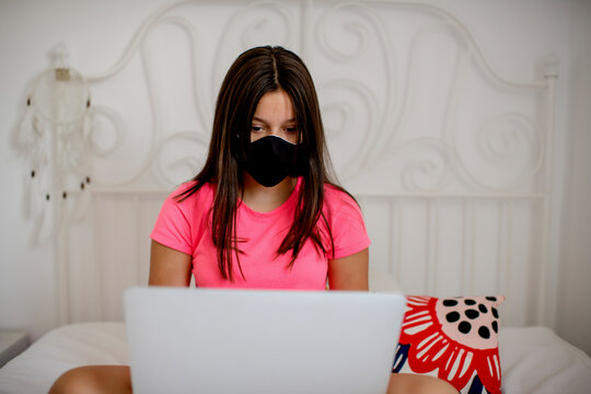 Teenage girl wearing protective face mask and studying at home quarantine due to the epidemic of Corona virus 