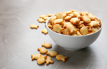 Delicious goldfish crackers in bowl on grey table