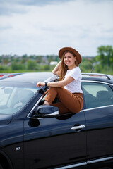 Beautiful blonde woman driver driving a black car. Concept of rich woman businessman freelancer.