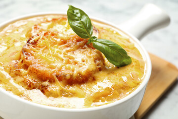 Tasty homemade french onion soup served in ceramic bowl, closeup