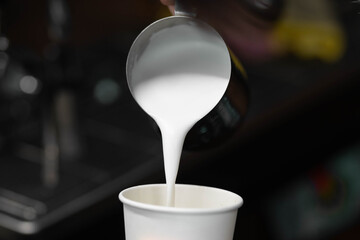 The process of making coffee on a coffee maker. Hot, frothed milk is poured from the pitcher into a...