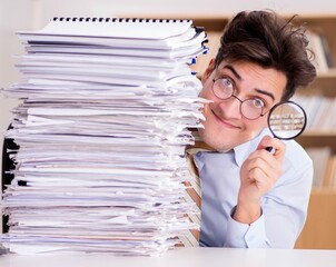 Funny auditor checking reports with magnifying glass