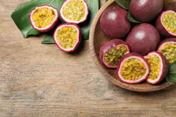 Cut and whole passion fruits (maracuyas) on wooden table, flat lay. Space for text