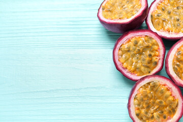 Halves of passion fruits (maracuyas) on light blue wooden table, flat lay. Space for text