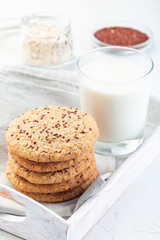Oatmeal and red quinoa cookies with glass of milk, on a wooden tray, vertical