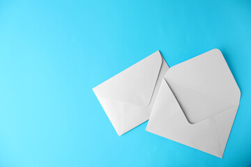 White paper envelopes on light blue background, flat lay. Space for text