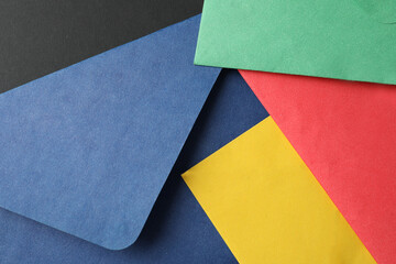 Colorful paper envelopes on black background, closeup