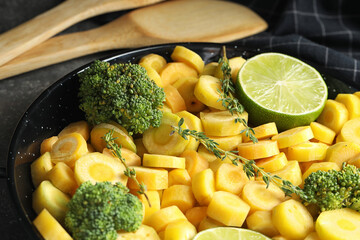 Raw yellow carrot with lime and broccoli in frying pan, closeup