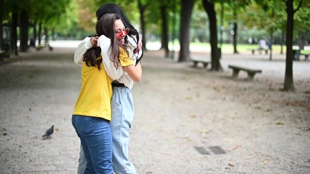 Ttwo girls hugging themselves tightly in a park - slow motion