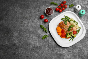 Tasty grilled chicken fillet with vegetables and sauce on grey table, flat lay. Space for text