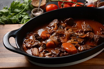 Beef Bourguignon in a pan. Stew with red wine ,carrots, onions, garlic, a bouquet garni, and garnished with pearl onions, mushrooms and bacon. French cuisine- regional recipe from Burgundy