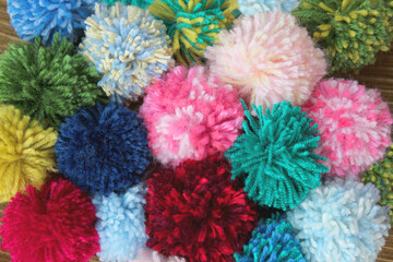 Fluffy colored wool pom-pom from threads for knitting yarn. Decorative balls made from wool. Handmade hobby crafts.