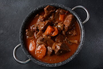 Beef Bourguignon in a pan. Stew with red wine ,carrots, onions, garlic, a bouquet garni, and garnished with pearl onions, mushrooms and bacon. French cuisine- regional recipe from Burgundy
