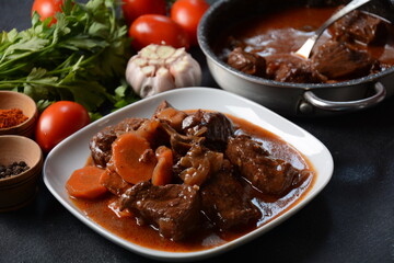 Beef Bourguignon in a pan. Stew with red wine ,carrots, onions, garlic, a bouquet garni, and garnished with pearl onions, mushrooms and bacon. French cuisine- regional recipe from Burgundy