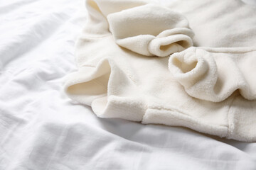 Warm fleece sweater on white crumpled fabric, closeup © New Africa