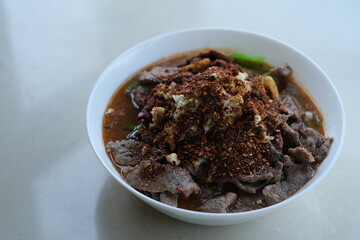 close up a bowl of Poached spicy slices of pork on white table. Famous Sichuan cuisine