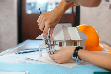 Engineering hands hold vernier caliper working and checking house model scale between meeting with businessman and businesswoman.