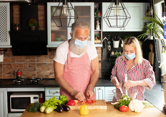 Happy caucasian aged couple cooking at home. Making salad at home. Home cooking. Social distance. Cooking during covid 19.