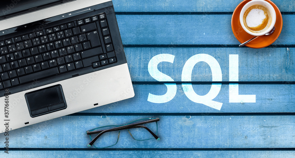 Poster sql programming language. word sql and laptop, glasses and coffee on wooden table