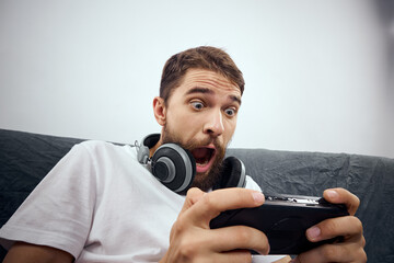 A man sits on a sofa with a gamepad in his hand. Leisure lifestyle game console