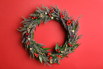 Fototapeta na wymiar Beautiful heather wreath with berries on red background, top view. Autumnal flowers