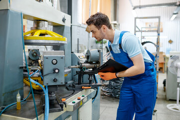 Worker at the machine tool makes bicycle rim