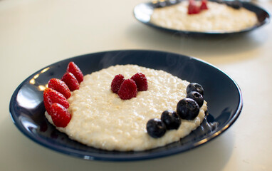 Oatmeal porridge with berries, in a blue plate. Healthy breakfast.
