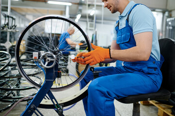 Male worker at the machine tool checks bicycle rim