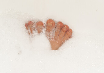 Female feet in soapy foam