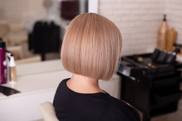 Female back with short straight natural blonde hair in hairdressing salon