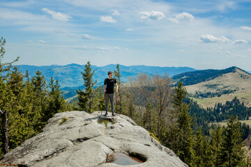 A mountain climber is high in the mountains against the sky, celebrating the victory, raising his...