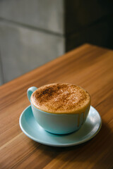 Hot cappuccino in coffee cup on the wooden table.