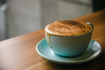 Hot cappuccino in coffee cup on the wooden table.
