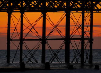 Sunset viewed through the structure of a pier