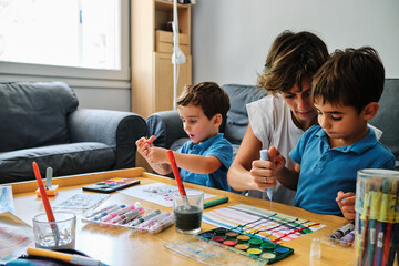 a mother helps her sons to draw and paint