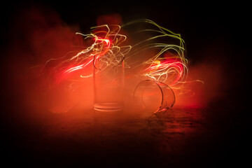 Broken glasses on wooden table at dark toned background with fog. Selective focus