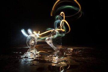 Broken glasses on wooden table at dark toned background with fog. Selective focus