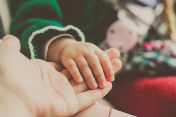 Primer plano de la mano de una mujer sujentando la mano de un bebé