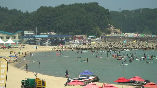 People learn how to surf in YangYang city beach South Korea near water breakers and red lighthouse, while no waves