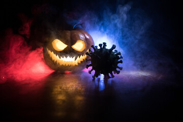 Fototapeta premium Halloween during Corona virus global pandemic concept. Glowing pumpkins and Covid novel on dark with thematic spooky decorations. Halloween pumpkin on foggy backlight.