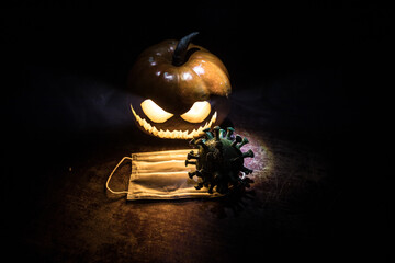 Halloween during Corona virus global pandemic concept. Glowing pumpkins and Covid novel on dark...