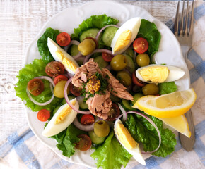 Tuna salad top view with eggs and cherry tomatoes, cucumber, and olives