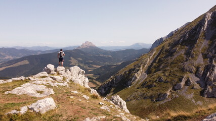 Naklejka premium man on a mountain summit taking a picture. Urkiola, basque country, spain